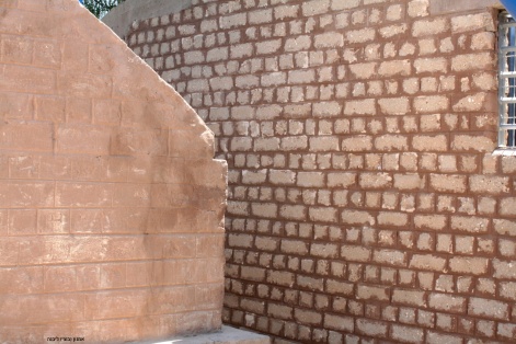 קיר בית הבאר שנבנה על ידי אנשי משאבים מימין, לצד מבנה מקורי של משאבת הבאר, הבריטי